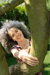 Smiling playful woman holding tree