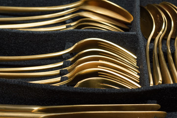 Gold colored cutlery in black cutlery tray