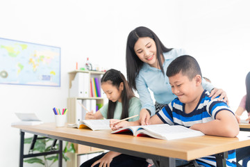 blurred asian students studying and do work with teacher in classroom, asian teacher teaching and explaining about how to do homework, happiness elementary school