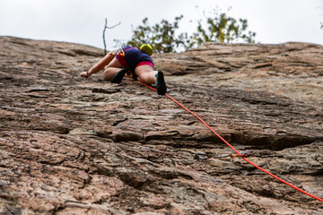 A worms eye selective focus perspective as a professional rock climber ascends a limestone cliff in...