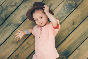 Portrait of happy cute little girl in rural style brown hat and muslin clothes in a summer day on...