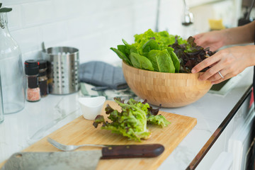 Young asian Woman Cooking in the kitchen. Healthy Food - Vegetable Salad. Diet. Healthy food and Lifestyle. Cooking At Home. Prepare Food.Young woman preparing vegetable salad in her kitchen.