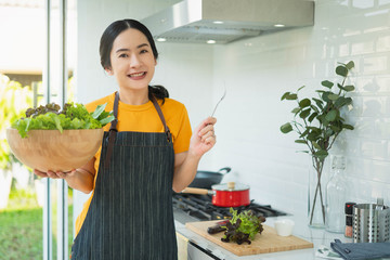 Young asian Woman Cooking in the kitchen. Healthy Food - Vegetable Salad. Diet. Healthy food and Lifestyle. Cooking At Home. Prepare Food.Young woman preparing vegetable salad in her kitchen.