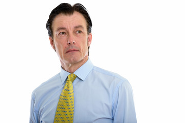 Studio shot of mature handsome businessman thinking while looking up