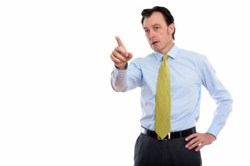 Studio shot of mature handsome businessman pointing at distance