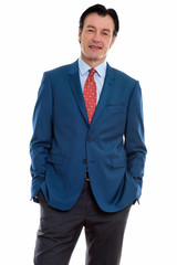 Studio shot of mature happy businessman smiling and standing