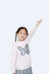 Little kid girl standing and points hand up present something on white background. Asian schoolgirl in education concept.