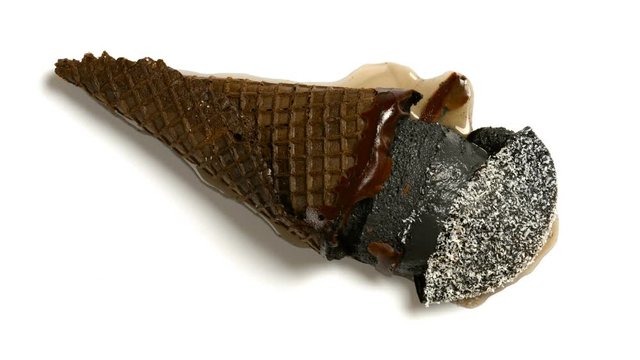 reverse of top view black color ice cream cone with shredded coconut melting on white background time lapse