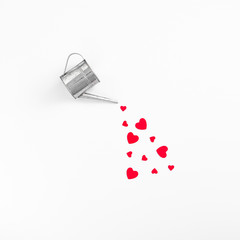 Silver watering can pouring red hearts