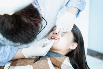 Fototapeta na wymiar Dentist examining teeth for young Asian woman