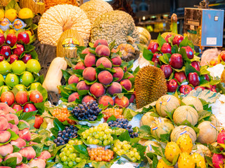 Shelves full of fresh fruits, close up view. Fruit market. Fresh fruits background. Apples, grape, peaches, muskmelons, pumpkins on market shelves. Selective soft focus. Blurred background