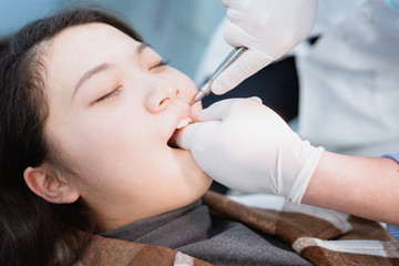 Obraz na płótnie Canvas Dentist examining teeth for young Asian woman
