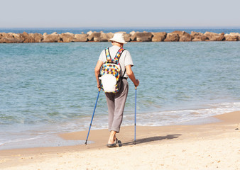An elderly man walks with nordic walking sticks