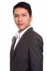 Profile view of young Asian businessman in suit looking at camera