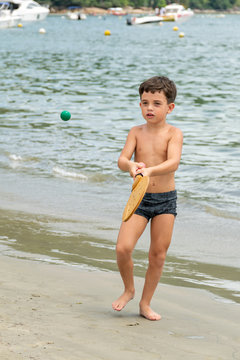 6 Year Old Boy Playing Racketball On A Sunny Day.