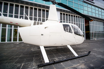side view of white commercial helicopter for private business service parking in front of landing point
