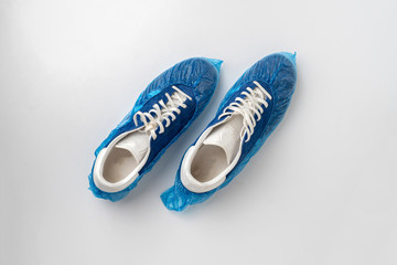 a top view of dirty boots sneakers or shoes in overshoes on the color surface, hygiene, clean medical hospital