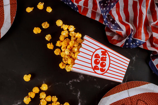 Caramel popcorn in striped box for watching american football game on tv.