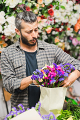 Florist at work: young man making fashion modern bouquet of different flowers