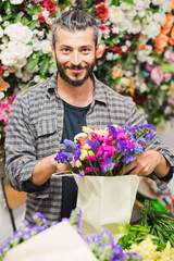 Florist at work: young man making fashion modern bouquet of different flowers