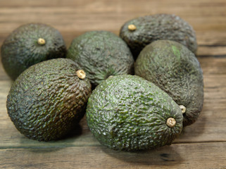 Fresh green avocados or Persea Americana on brown wooden background.  Vegetarian and fruit food image.