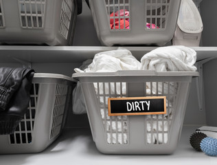 Dirty laundry sign on basket in laundry room. Multiple laundry baskets on shelve. Chalk board sign...
