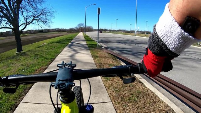 Biking Time-Lapse - turning corner on concrete hike & bike trail, long straight section with dry grassy empty pond on the left - Five-X speed Hyper-lapse