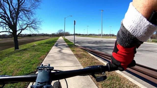 Biking Time-Lapse - turning corner on concrete hike & bike trail, long straight section with dry grassy empty pond on the left, down hill towards S-curve - Five-X speed Hyper-lapse