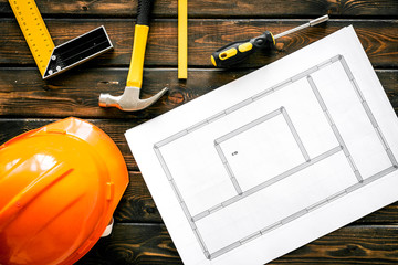 House building plan. Blueprints, instruments, helmet on dark wooden background top-down