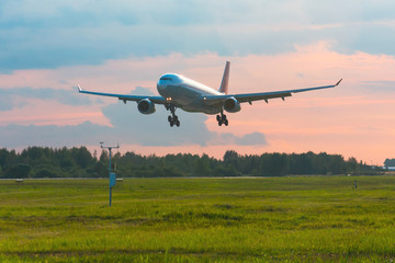 Fototapeta na wymiar Passenger airplane landing on runway at airport, early evening.