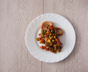 plate of grilled meat with vegetables on white wood background, top view