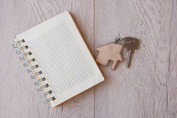 House key with home keyring on wood background, copy space
