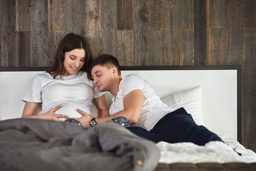 A young married couple awaiting a baby. Beautiful couple lying in the bedroom make plans for the...