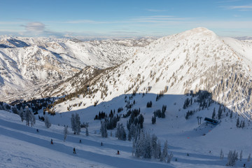 Skiers and snowboarders on slope viewed from Hidden Peak at Snowbird in Little Cottonwood Canyon in the Wasatch Range near Salt Lake City, Utah, USA. - obrazy, fototapety, plakaty