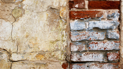 concrete wall texture of an abandoned old house in crumbling and peeling beige stucco with gray cement