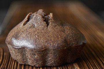 Homemade chocolate muffin on a wooden board. Dark wooden background, closeup, selective focus