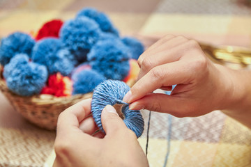 Handmade pompons. The process of making pompons from threads by woman
