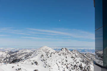 The moon and mountains viwed from top of Hidden Peak in winter at Snowbird in Little Cottonwood...