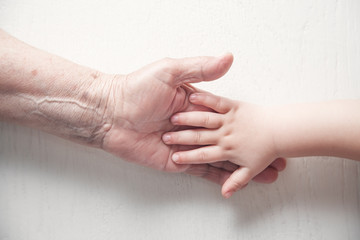 Elderly woman and a kid hands together.