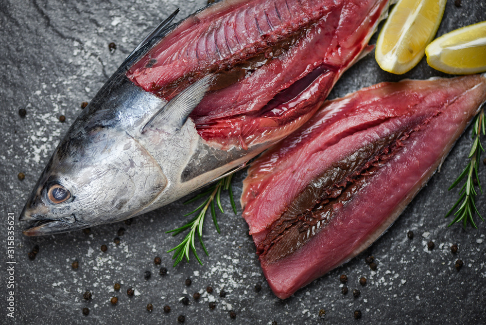 Wall mural fresh fish fillet sliced for steak or salad with herbs spices rosemary and lemon / raw fish seafood 