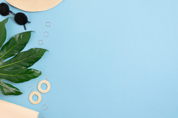 Summer flat lay composition with place for your text. Frame made of green leaf, straw hat, sunglasses.