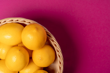 Ripe lemons on bright pink paper background