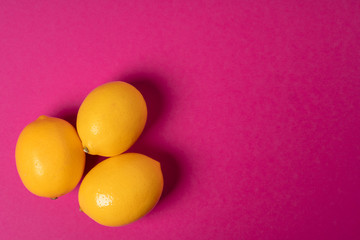 Ripe lemons on bright pink paper background