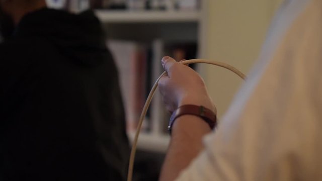 A cable wrangler holds a BNC cable while a camera crew films a TV show.