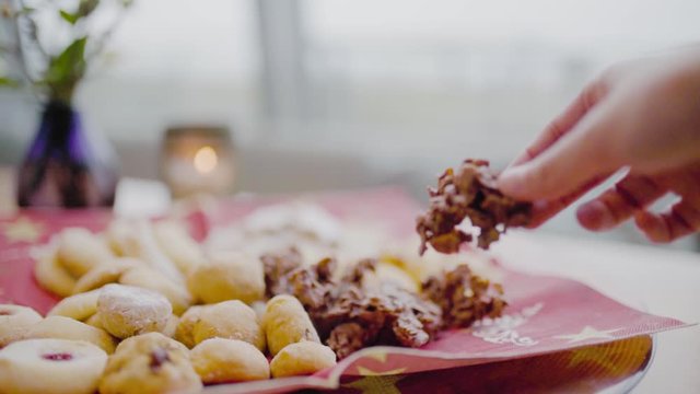 Woman's hand reaches for cookie biscuit with candle in background