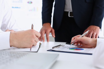 Group of people hold silver pen ready to make note in clipboard pad sheet closeup. Training course...