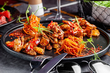 Indian kitchen. Fried chicken slices with curry sauce, hot red pepper and vegetables. Modern serving dishes in the restaurant. background image, copy space text