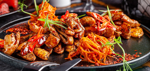 Indian kitchen. Fried chicken slices with curry sauce, hot red pepper and vegetables. Modern serving dishes in the restaurant. background image, copy space text