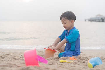 A boy is playing sand and swimming with his brother on the beach.