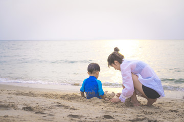 A mother is playing sand and swimming with her son on the beach.